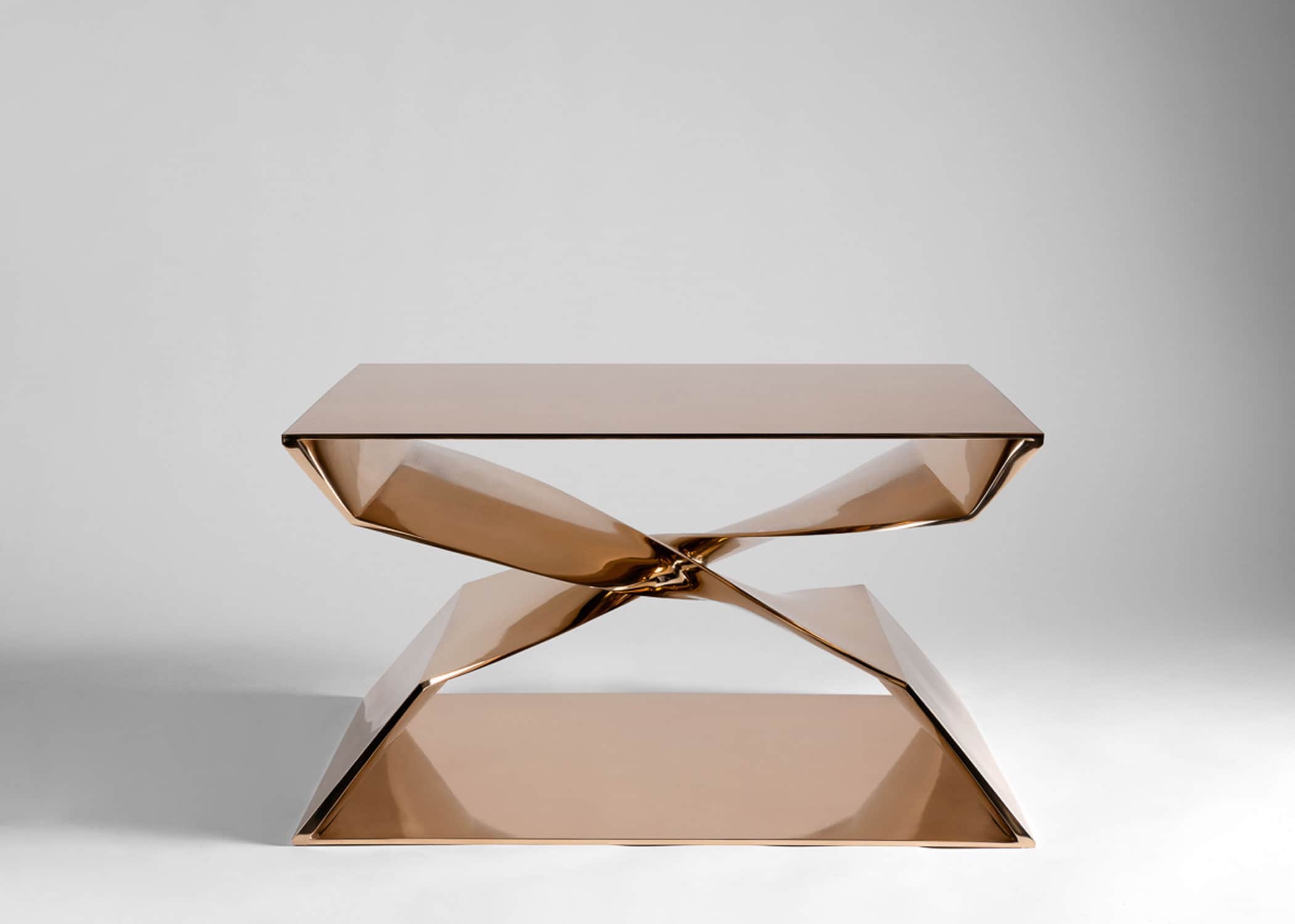 This image shows a front elevation view of the CE24 Cast Silicon bronze cast X shaped coffee table, mirror polished finish designed by Carol Egan.  Dimensions are 30" w x 24" d x 18"h.  The table is shown against a grey background.  The table consists of two interlocked cast forms that make an X shape.