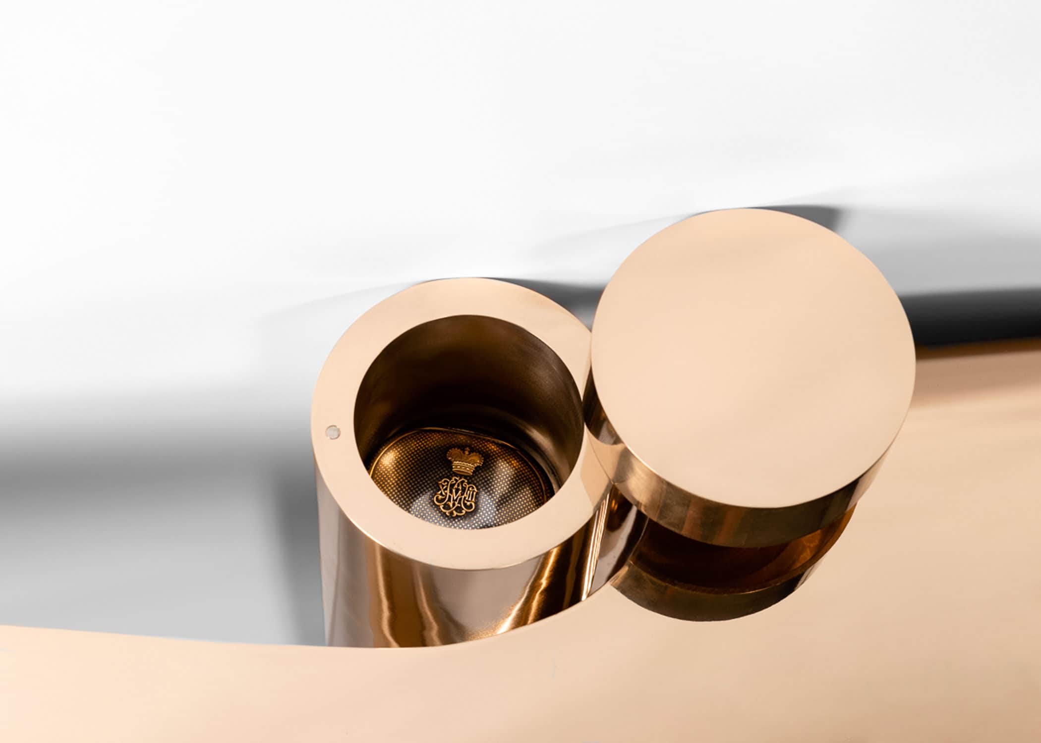 This image shows a detail looking into the storage cylinder of the double emperor, flying shelf, machined silicon bronze designed by Carol Egan.  The dimensions of the piece are 20.5"h x 84"w x 18"d (52 x 213 x 46cm). Wall-mounted two-tier console with cylindrical edging wrapping perimeter of shelves with cut out at the wall, cylindrical form flanking cutout with concealed storage.  View detail of top of cylinder in open position.