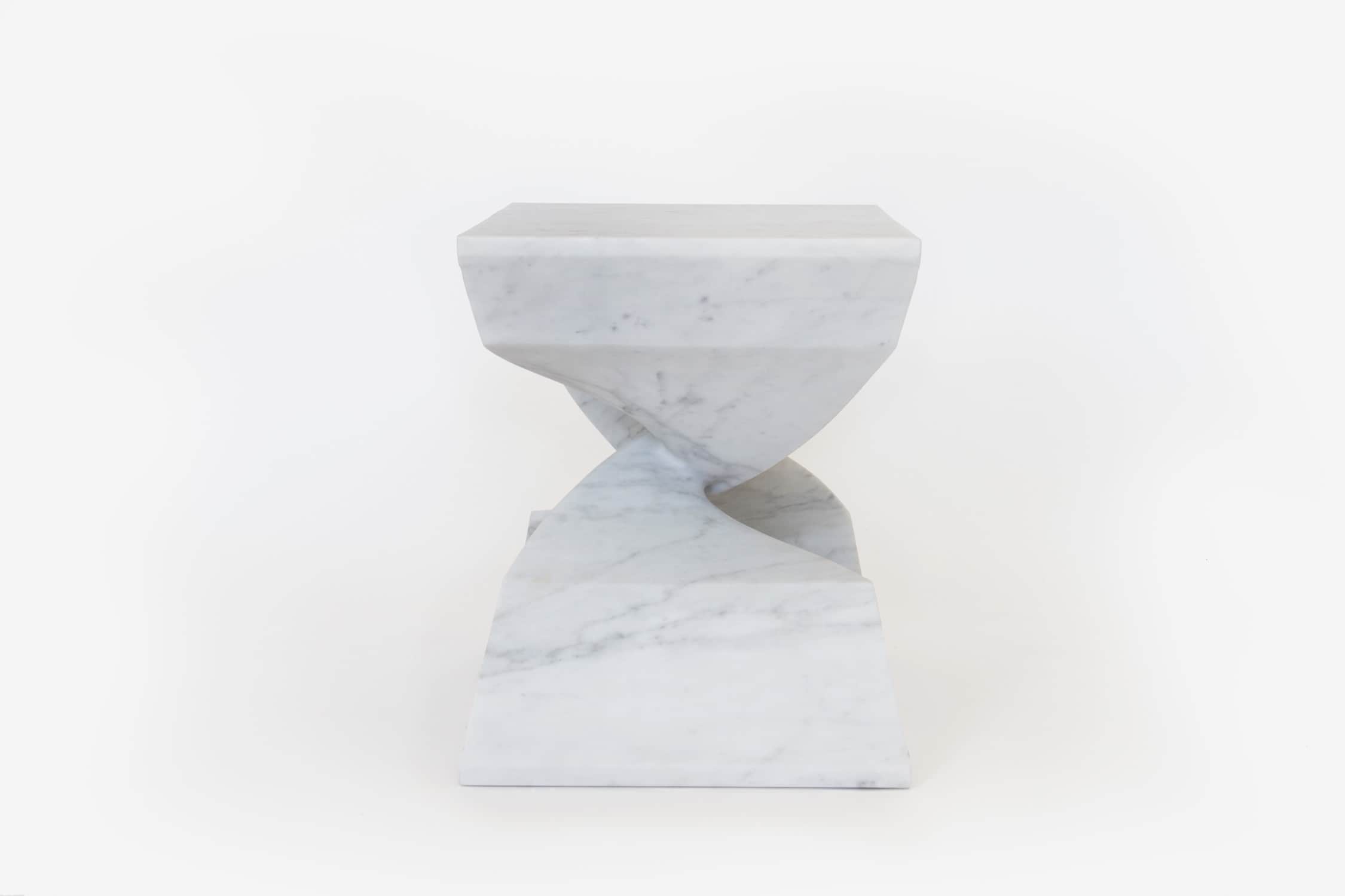 The image shows a side elevation of the CE06 X -STOOL, hand carved in Carrara Marble designed by Carol Egan.  Shown in this image against a grey background.  The dimensions of the piece are 18"h x 22"w x 15"d (46 x 56 x 38cm).