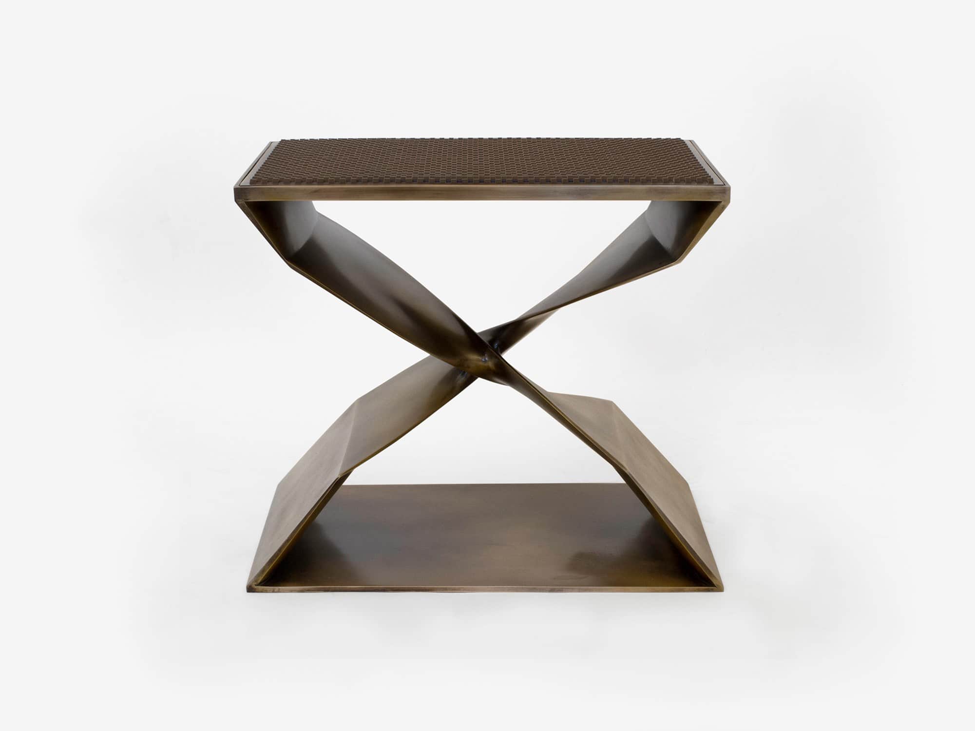 Designed by Carol Egan this image displays a view of the front elevation of a customized CE06 X Stool with a statuary bronze and woven leather seat.  The leather is a chocolate brown color and is interwoven in a grid pattern on the seat top.   The dimensions of the stool are 18"h x 22"w x 15"d (46 x 56 x 38cm).
