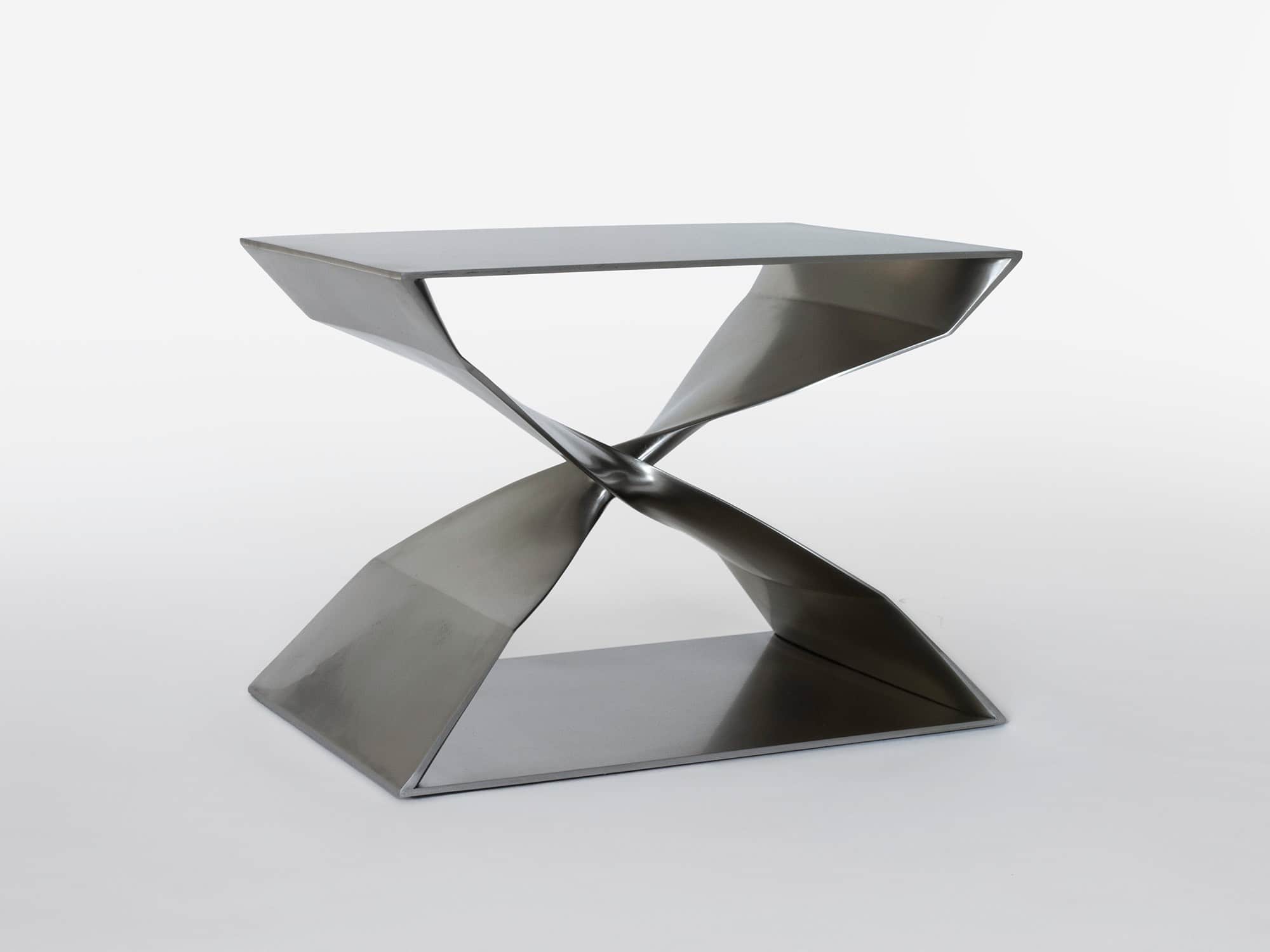 Designed by Carol Egan, the stainless steel X bench CE06 X- Stool is shown here against a grey background.  The dimensions of the piece are 17"h x 22"w x 15"d (44 x 56 x 38cm).