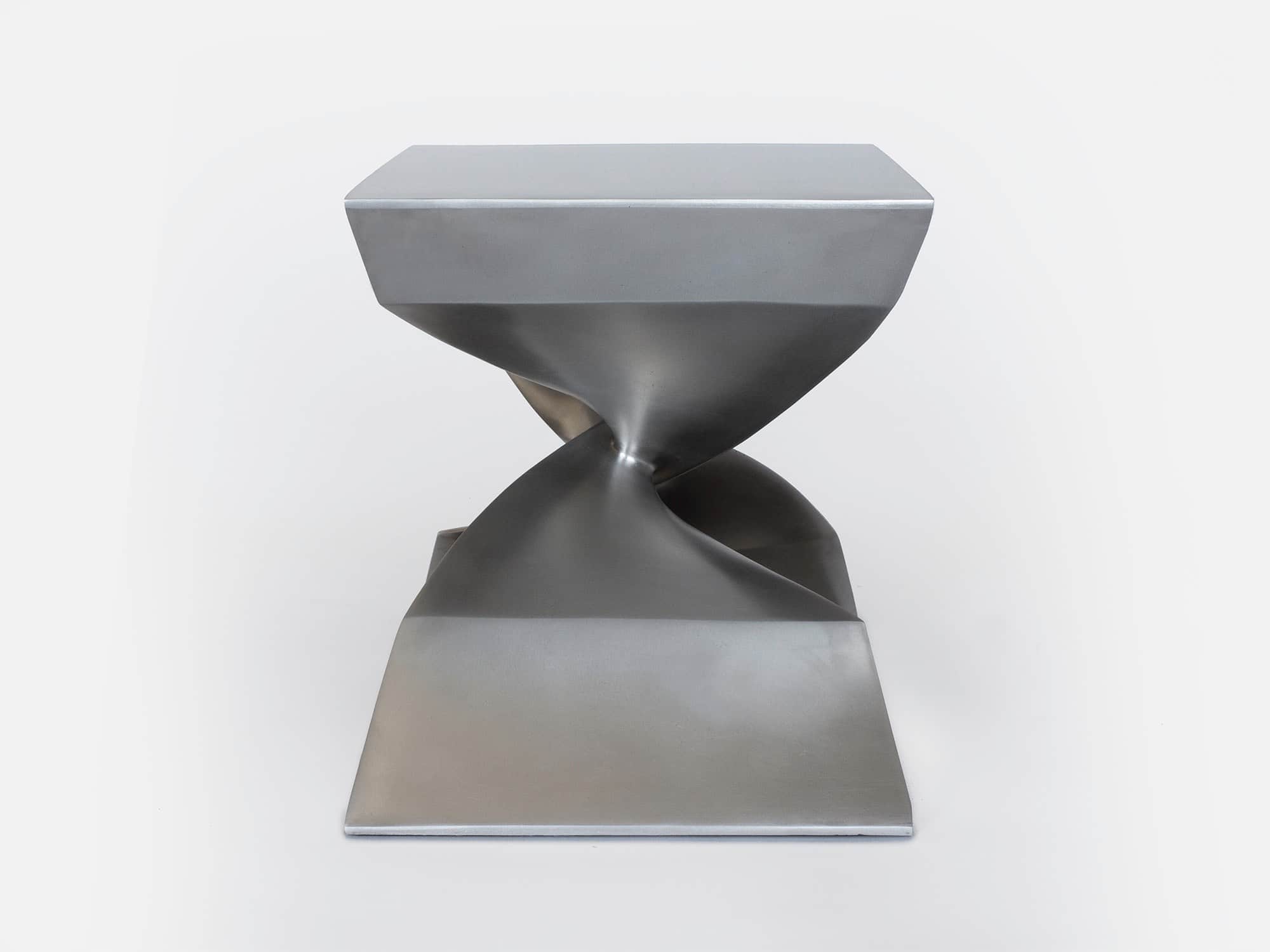Shown in this image is a side elevation of the CE06 X Stool in a stainless steel finish.  Fabricated by lost wax casting process the dimensions of the stool are 17"h x 22"w x 15"d (44 x 56 x 38cm).
