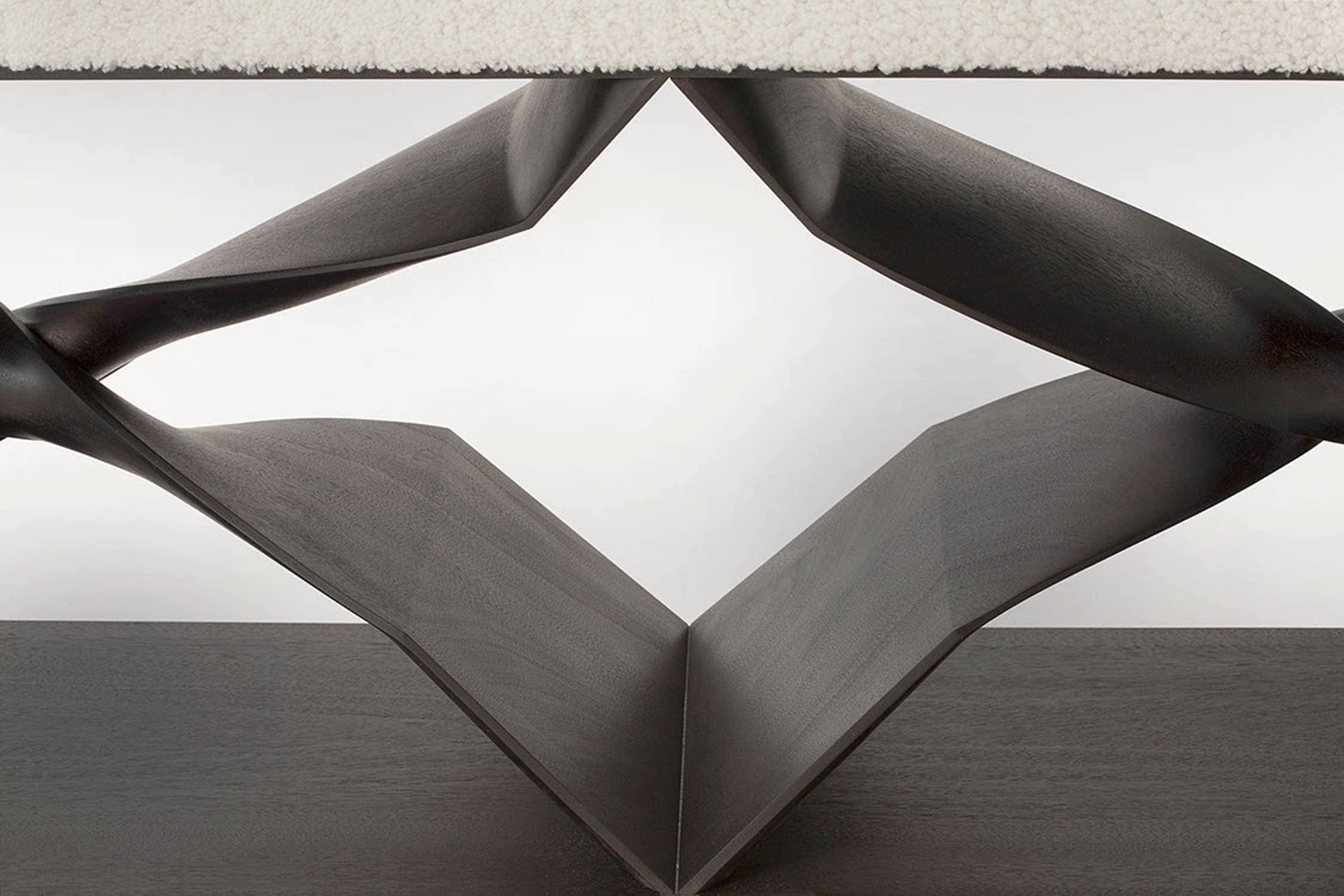 Designed by Carol Egan this image shows a detail of the carved double x intersection of the CE07 XX Bench is an ebonized Mahogany finish.  18"h X 44"w X 15"d (46 X 112 X 38cm).