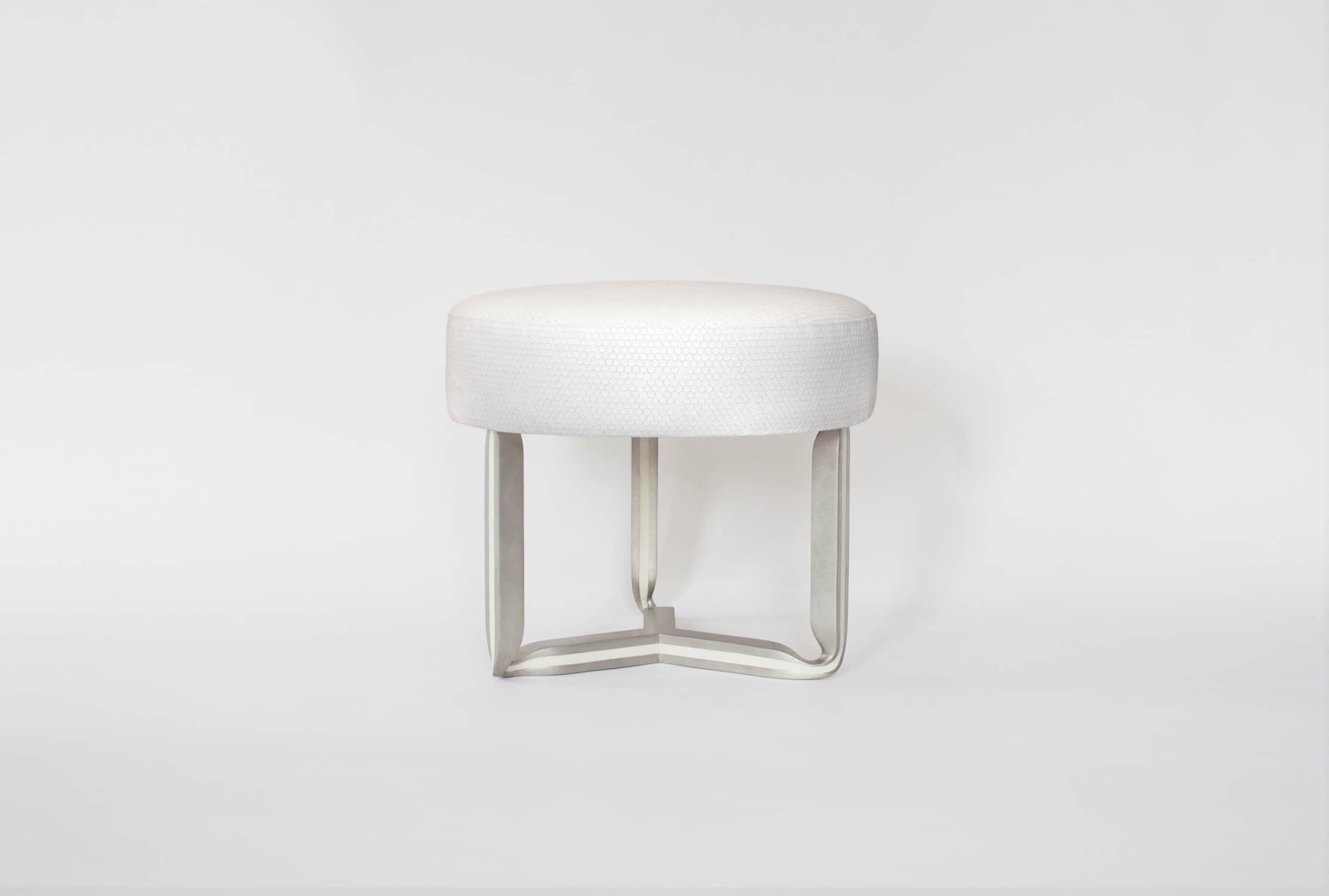 The CE17 Ottoman is shown here in a cast stainless steel and recycled white resin inlay with a custom stamped octagonal white leather seat top.  Designed by Carol Egan, the dimensions of the piece are 17"h X 21"w X 21"d (44 X 54 X 54cm).