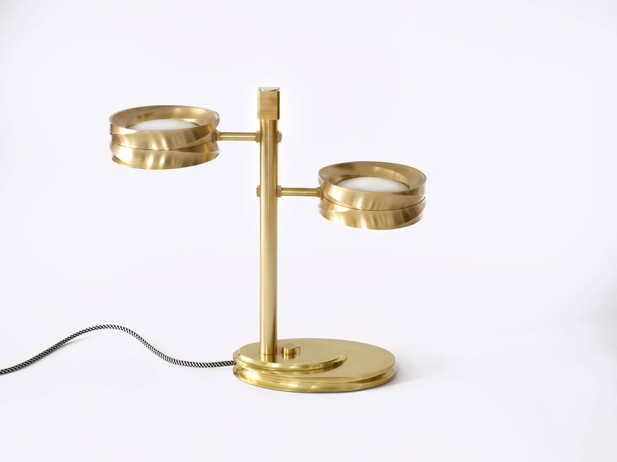 Machined bronze and frosted milk glass table lamp entitled "Double Bubble" table lamp is shown against a grey background.  Fitted with LED bulbs and a checkered black and white silk chord, the dimensions of the table lamp are 17"h X 18"w X 7"d (43 X 46 X 18cm).