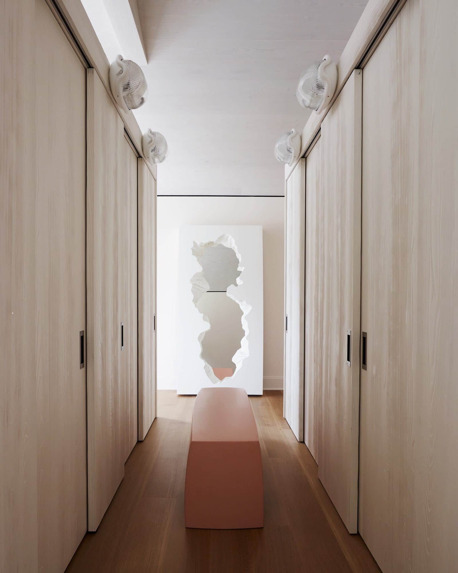 In this image shows a dressing room designed by Carol Egan in sand blasted Doug Fir custom millwork.  Vintage FLOS Noce lamps by Achille Castiglioni lights the room.  A Rudolf bench by Pierre Yovanovitch sits in the middle of the room with a "Broken" mirror by Snarkitecture for Gufram at the opposite end.