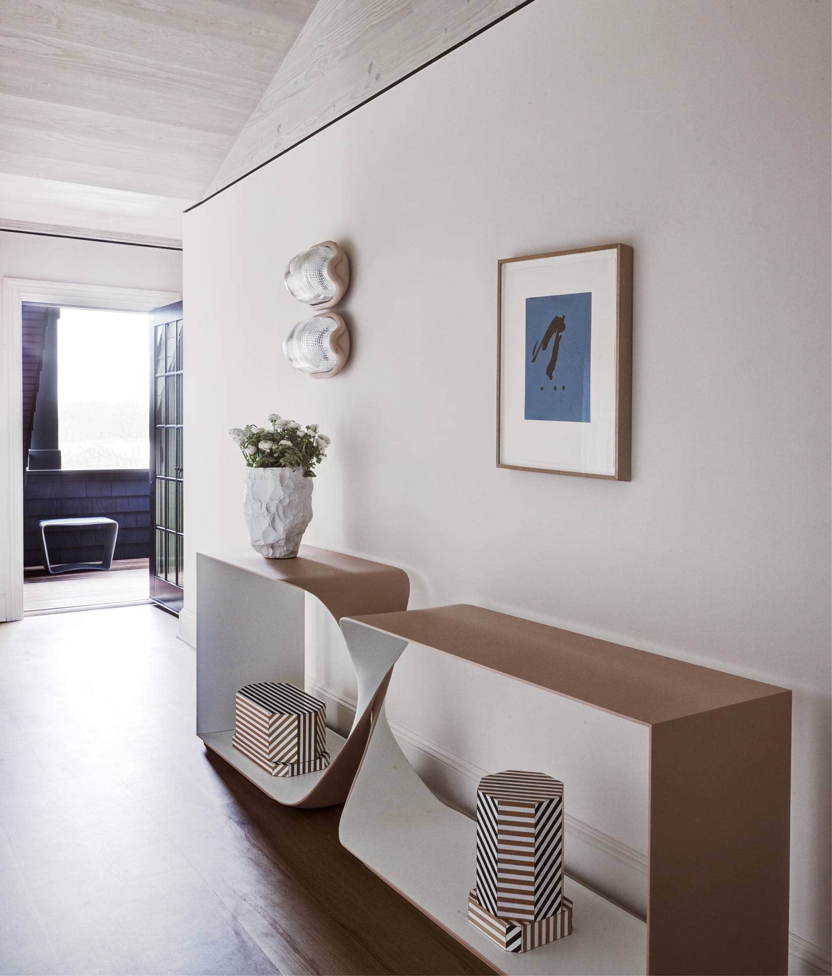 Designed by Carol Egan, this image shows a two-tone painted CE12 Freestanding Console accessorized by a houses Crockery Posy tall vase by Max Lamb and Ziggurat containers by Oeuffice.  There are a pair of Noce lamps by Achille & Pier Giacomo Castiglioni stacked one on top of the other and a framed Lithograph by Robert Motherwell hanging above the Freestanding console.  The walls are painted a pale plaster color and the flooring is wide plank Oak.