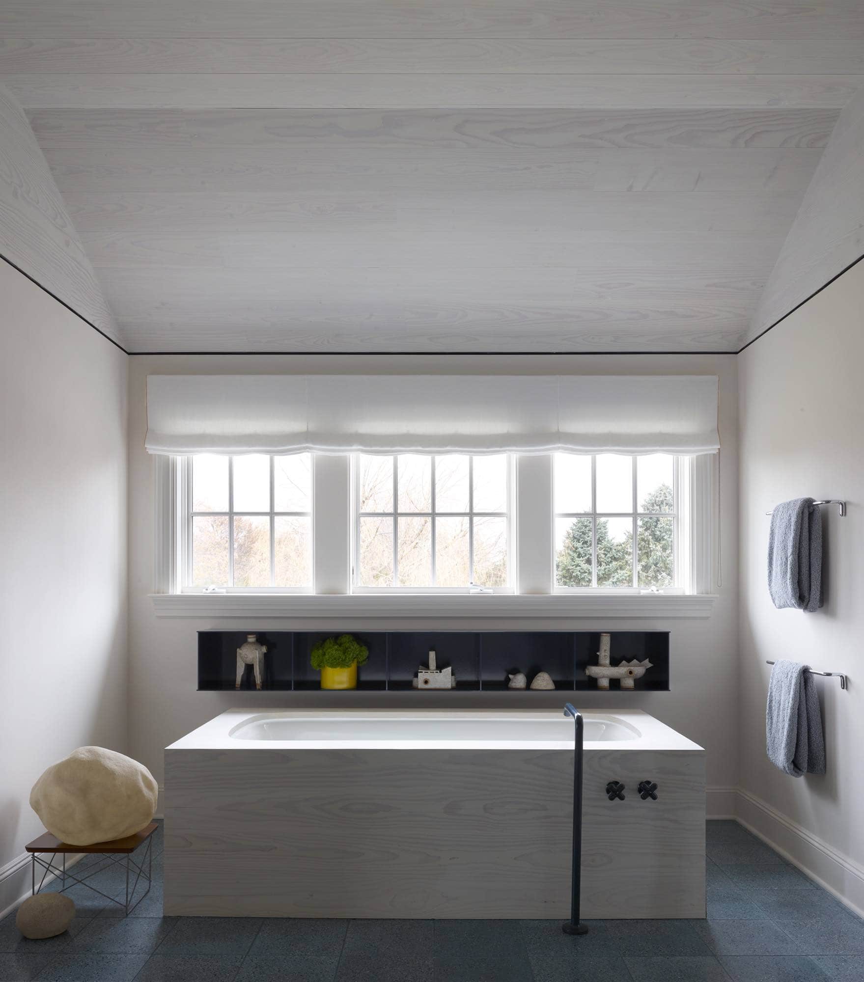 Shown here is an image of the master bathroom designed by Carol Egan.  The tub is paneled in Dinesen Doug Fir and there is a tub filler in a navy-blue powder coat finish that coordinates with the navy blue Fantini X shaped faucets.  Behind the tub is a wall hung metal display cabinet by Jonathan Nesci which houses ceramics by Carlos Otero and porcelain vase by Bodil Manz.   The bathroom floor is an agate blue Terrazo Field tile supplied by Urban Archaeology.