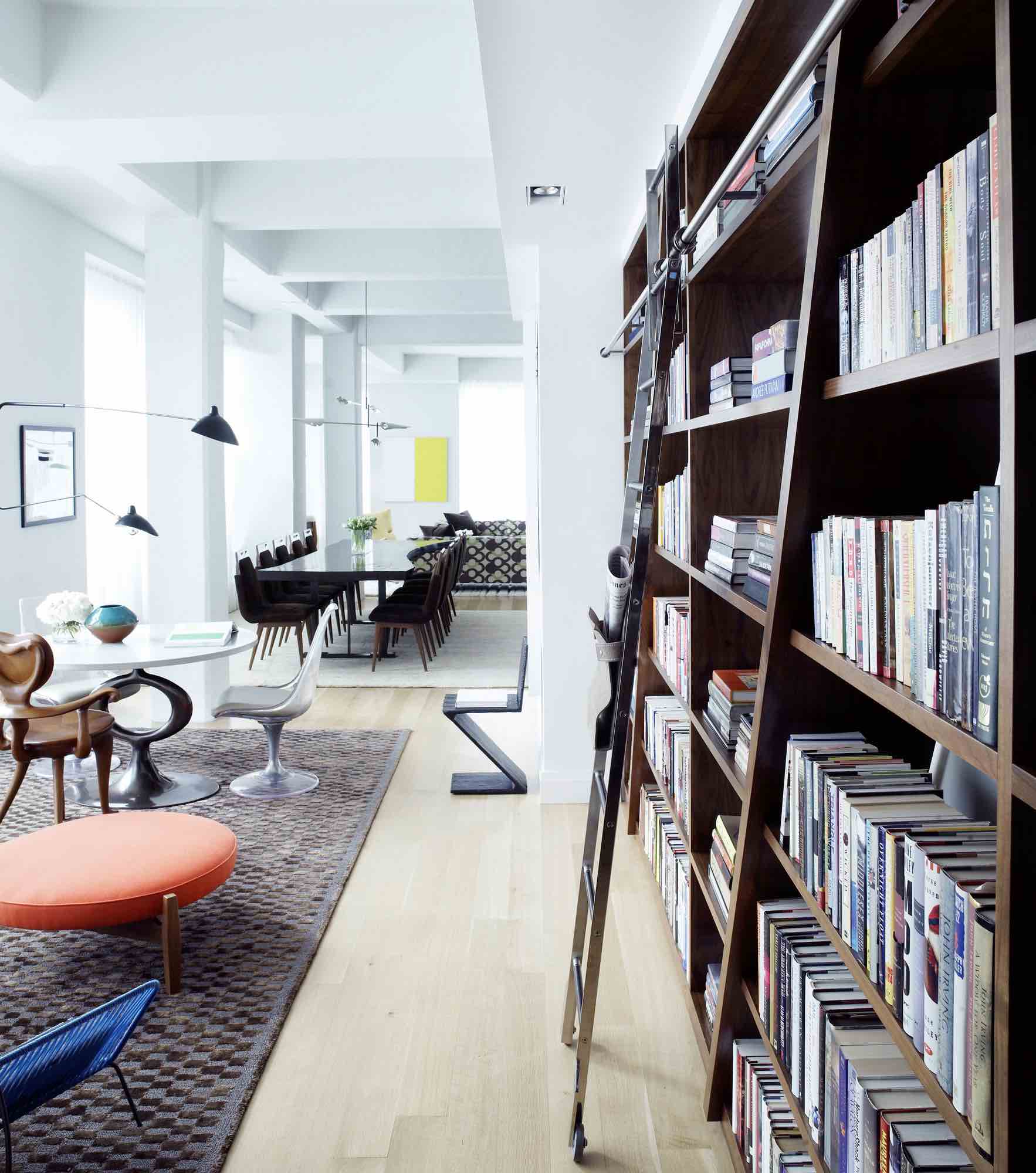 Featured in this image is the entry hallway of a tribeca loft designed by Carol Egan.  The hallway is lined with a custom 14 ft high walnut library wall that is fitted with a steel rolling ladder.  The floors are wide plank white oak in contrast with the library.