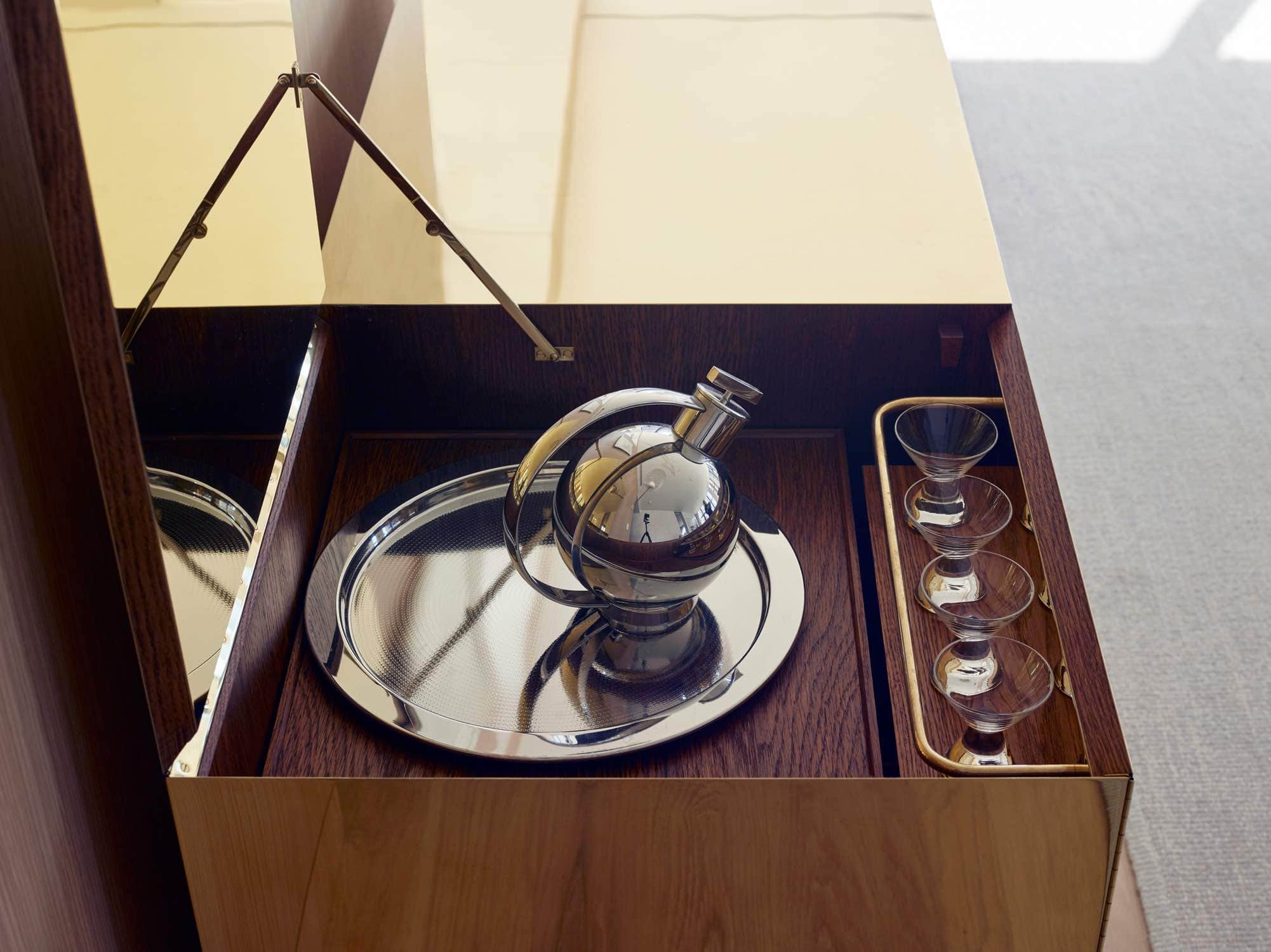 This image shows a detail of the interior of the Brass cabinet by Ilse Crawford.  The interior of the cabinet is fabricated from Walnut and brass fittings.  This is a signature piece of furniture in the Loft designed by Carol Egan Interiors.