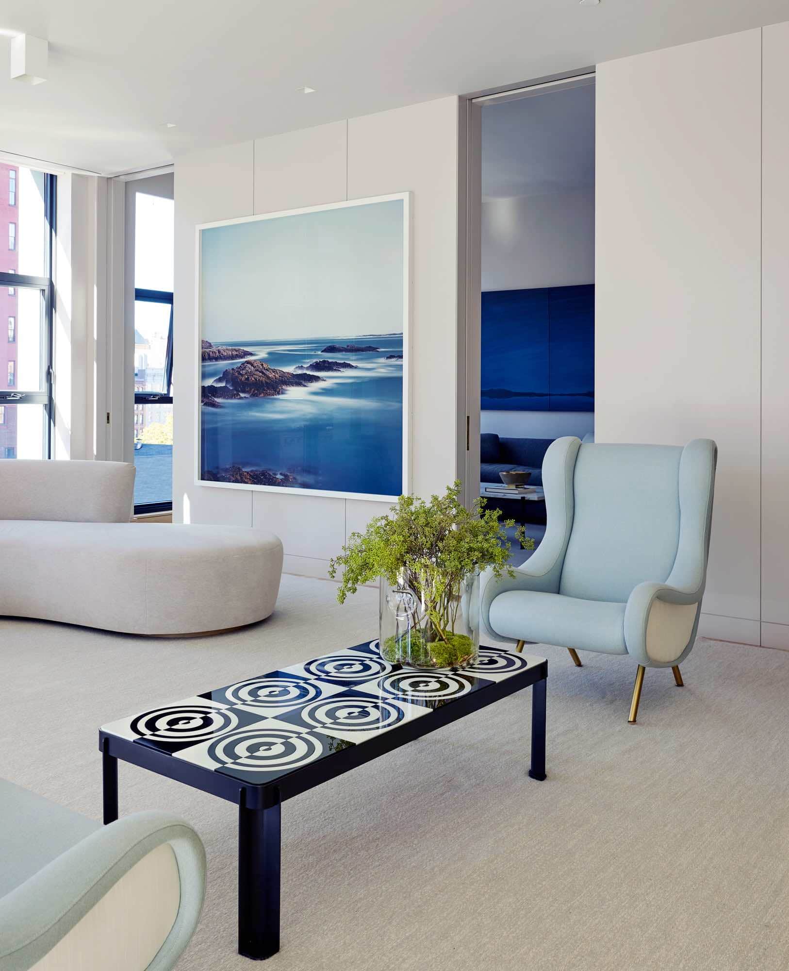 This image shows the living area of the loft from a different angle facing into the adjoining Family TV room through pocketed doors.  Two Vintage Senor Chairs are flanked by a Robert Riida Murano glass optical top and metal coffee table.  Artwork by Darren Almond in the background.