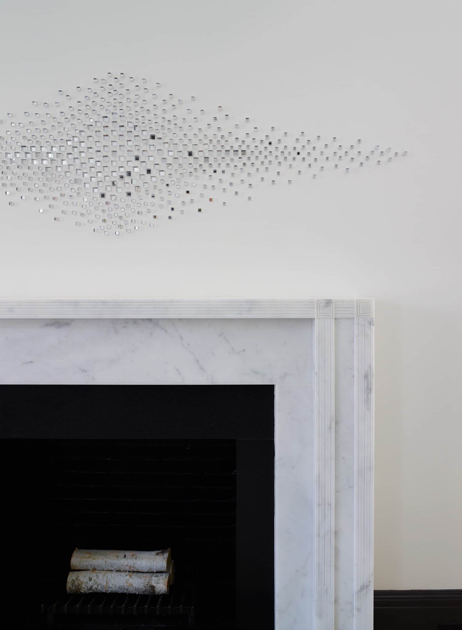 In the living room of this Sutton Place residence designed by Carol Egan, this image is a detailed view of the Carrara marble Mantlepiece and "Mirage" glass sculpture by Teresita Fernandez.