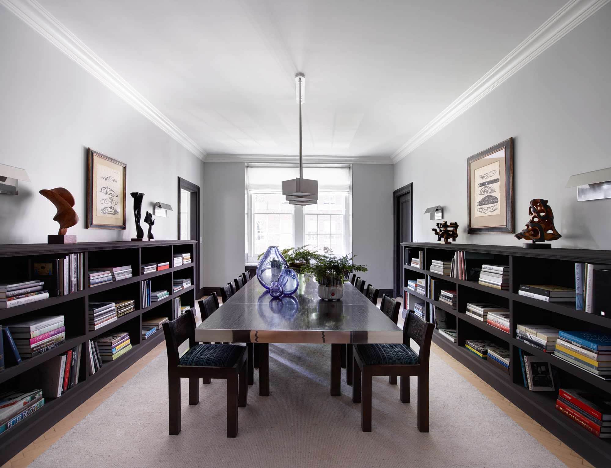 This image shows a dining room designed by Carol Egan in this Sutton Place apartment with a custom dining table by Studio Carol Egan surrounded by dining Chairs by Carlo Scarpa on a custom wool and grey silk area rug by V`Soske.  The "Grand Modele" wall sconces by Christophe Gevers and ceiling Light by Paavo Tynell light the room.