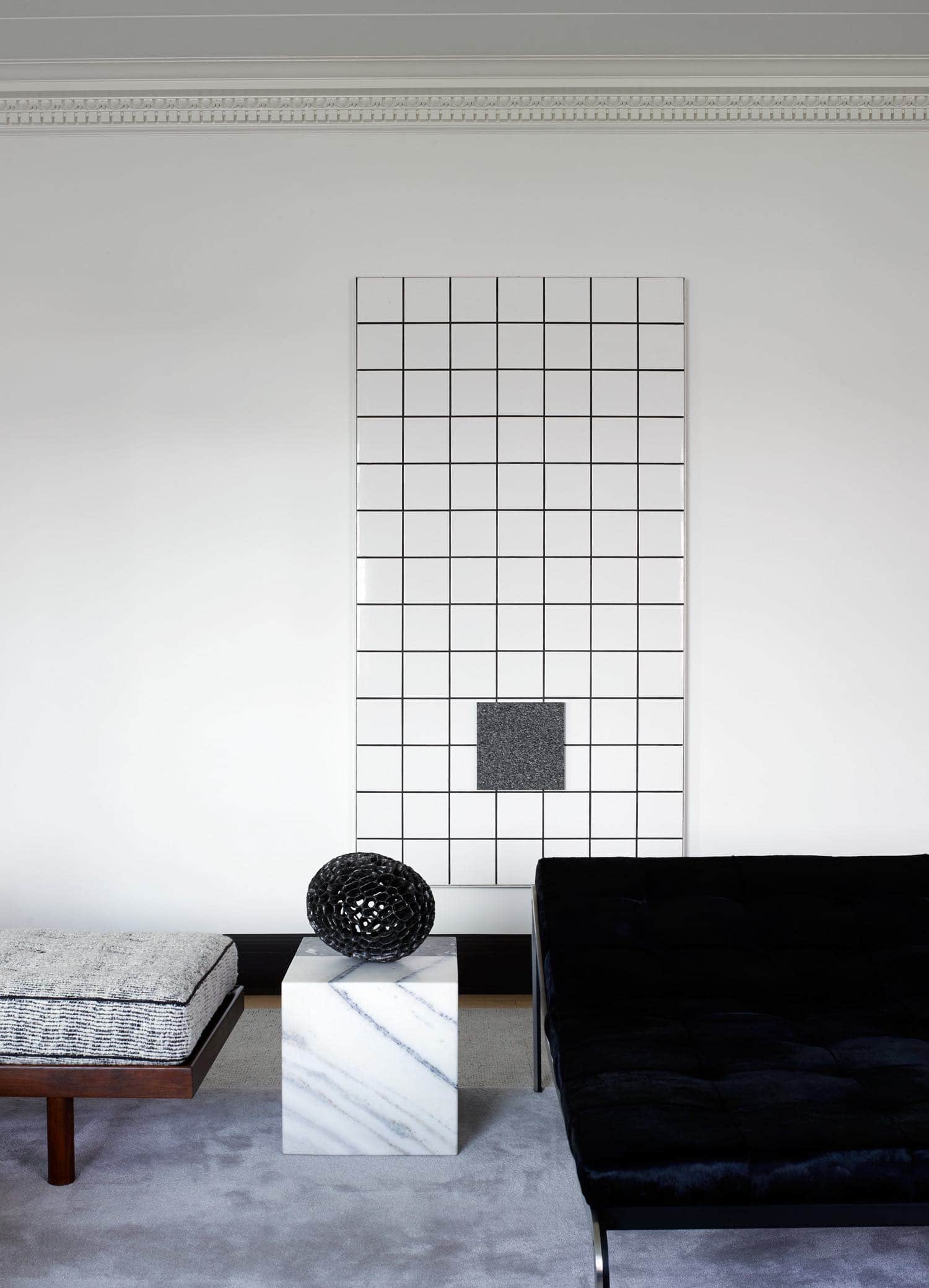 Shown in this image is a view of the living room designed by Carol Egan with the Centre Pompidou tile artwork by Jean Pierre Raynaud hanging on the wall.  The Terrell side table is a black and white marble block and sits between a Pierre Paulin day bed and a Charlotte Perriand daybed with a custom area rug by V’Soske carpets.