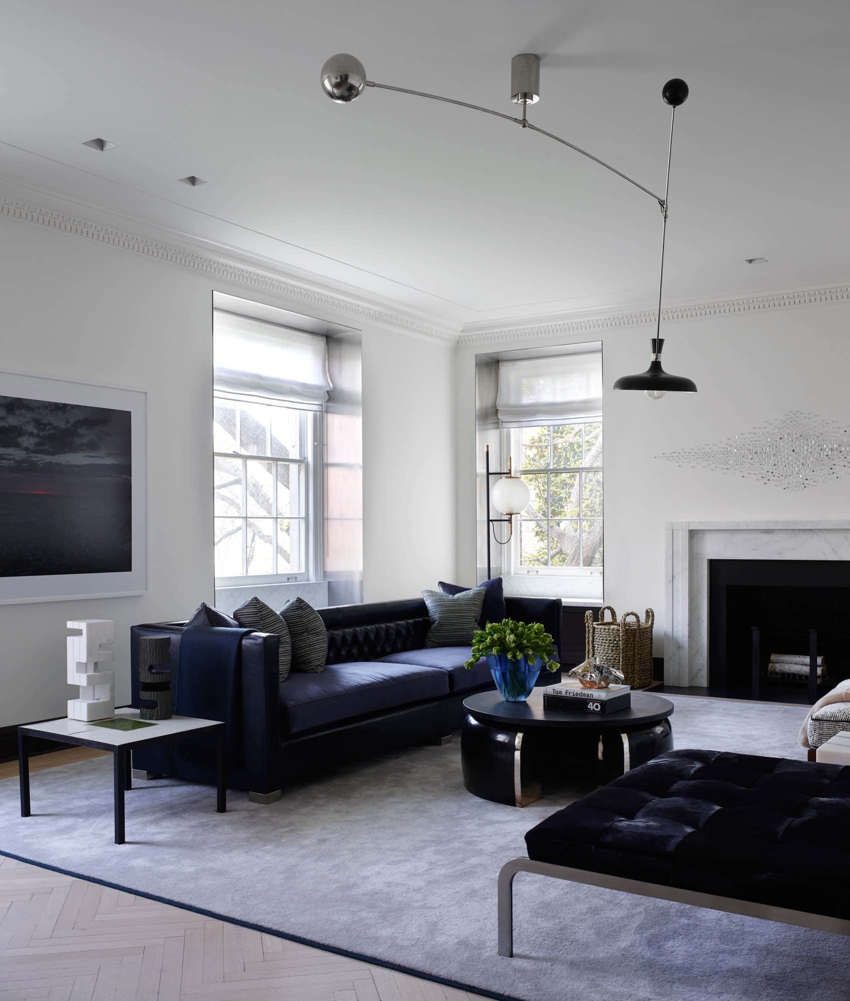 Shown in this image of a Sutton Place residence designed by Carol Egan is the living room with a Marianne Vissiere hand-made coffee table in white and avocado green ceramic tiles and black iron base beside a custom sofa design by Carol Egan.  The Dust Series artwork by Nadav Kander hangs on the wall behind the sofa.  Above the Bracelet coffee table by Eric Schmitt hangs a Mobile light by Fedele Papagni.