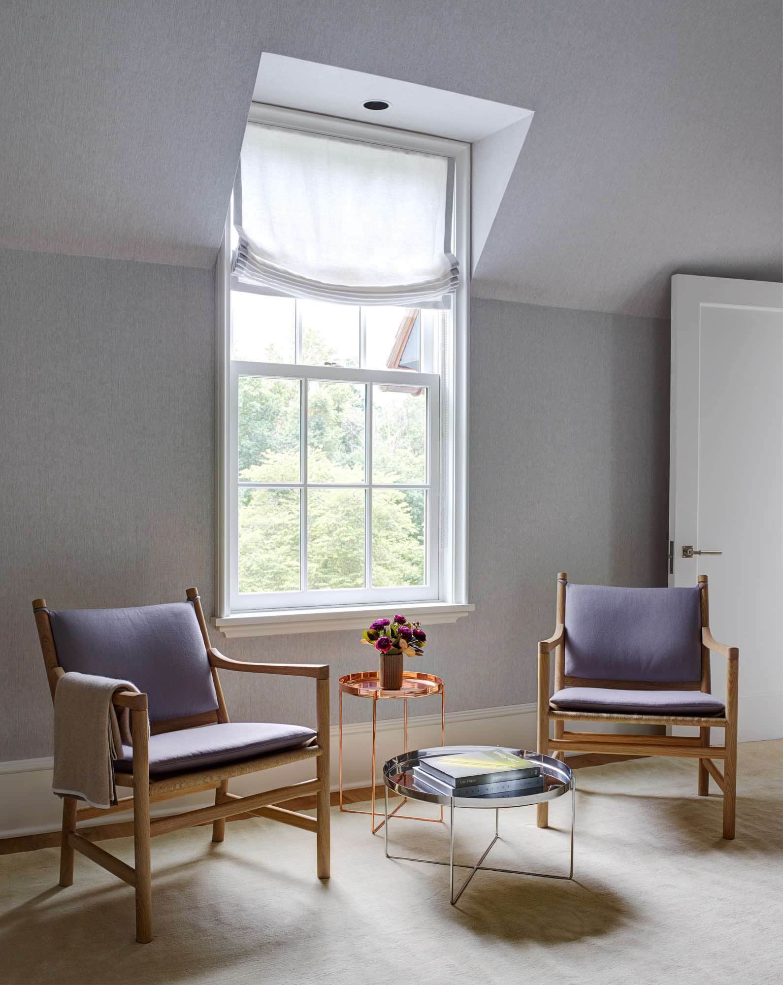 Designed by Carol Egan, this image is of a guest bedrooms sitting area with ladderback chairs in oak by Hans Wegner and E15 Habibi tray side tables by Karkula.  The walls of the room are upholstered in a natural linen and the chairs flank the window overlooking garden views from the 2nd floor.