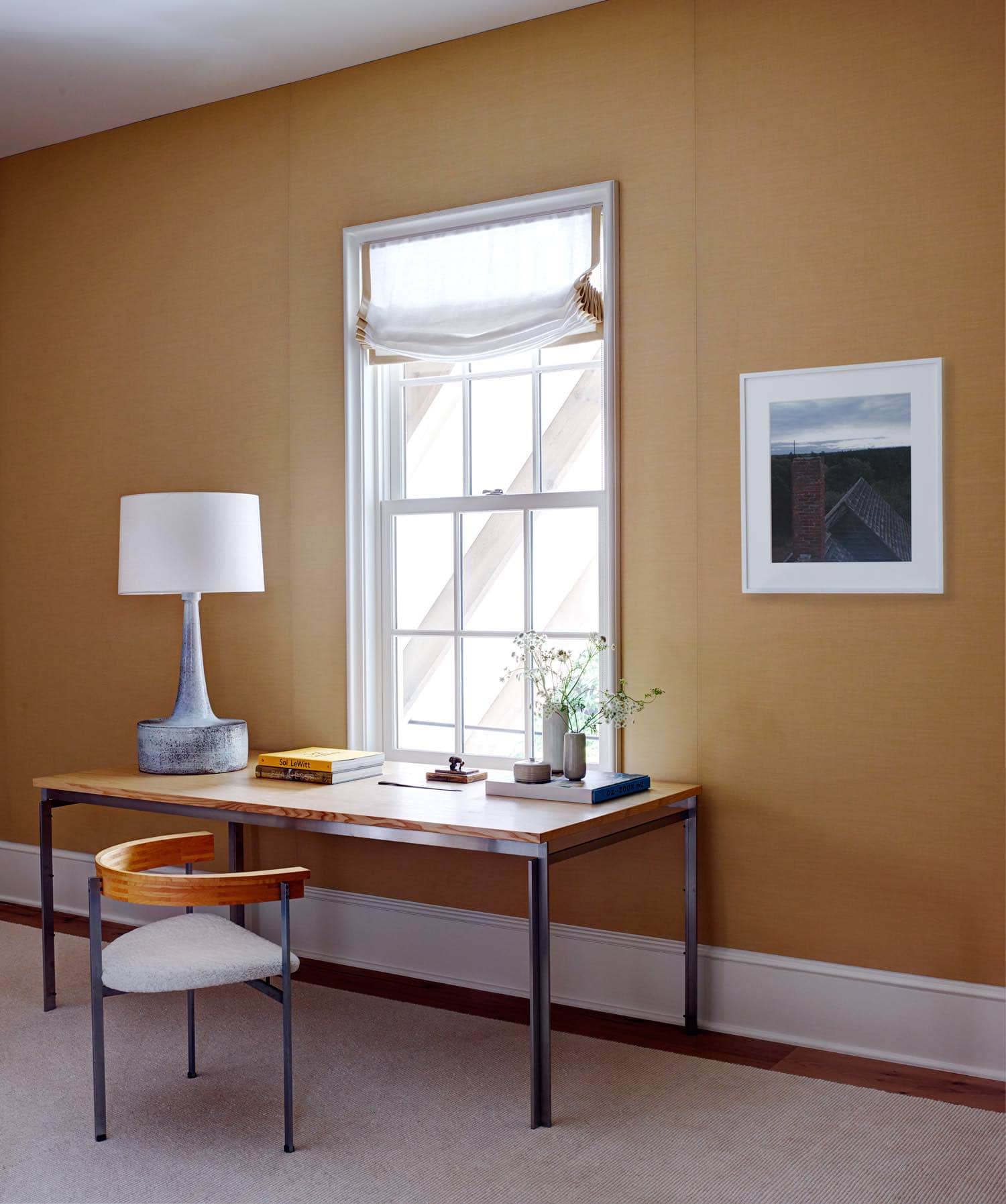 Designed by Carol Egan, the image shows a sunny guest bedroom upholstered in a sunset yellow wool with contrasting white trimmed millwork accents.  The guest bedroom has 1955 PK55 Students desk and 1957 PK11 chair by Poul Kjaerholm which overlook garden views through the 2nd floor window.