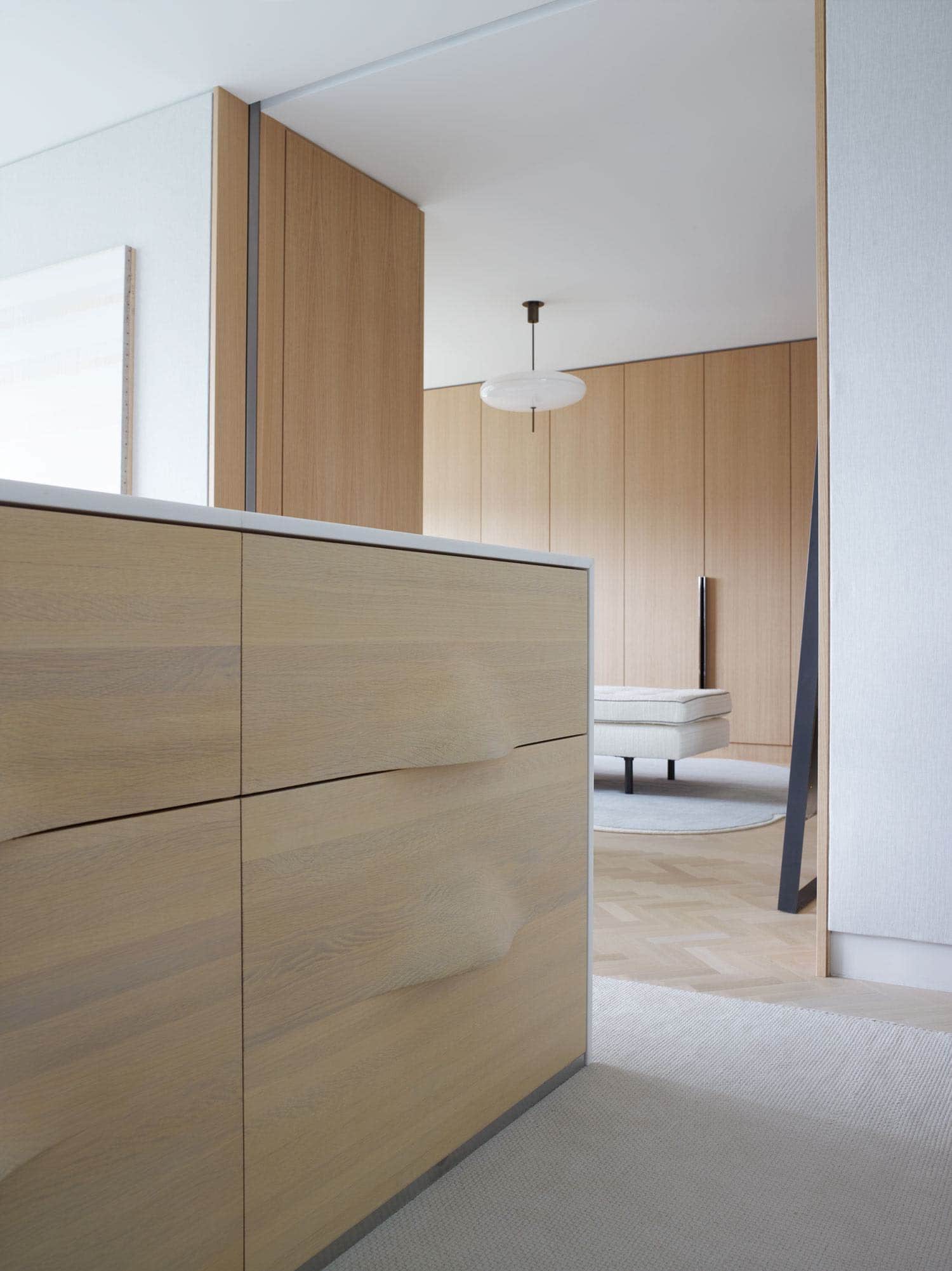 Shown in this image is a detail of a cabinet headboard design by Studio Carol Egan in the master bedroom of a fifth avenue apartment in New York city which overlooks Central Park.  The drawers of the cabinet are carved Oak with an undulating pattern.