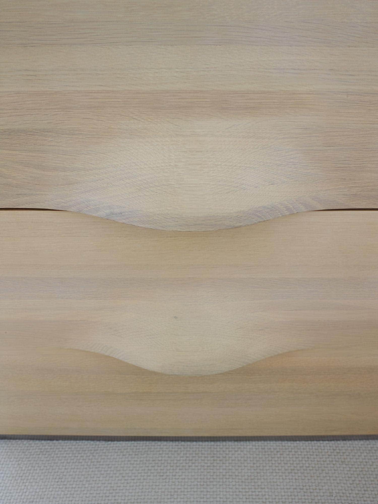 Shown in this image is a detail of a cabinet headboard design by Studio Carol Egan in the master bedroom of a fifth avenue apartment in New York city which overlooks Central Park.  The drawers of the cabinet are carved Oak with an undulating pattern which integrates the drawer pull.