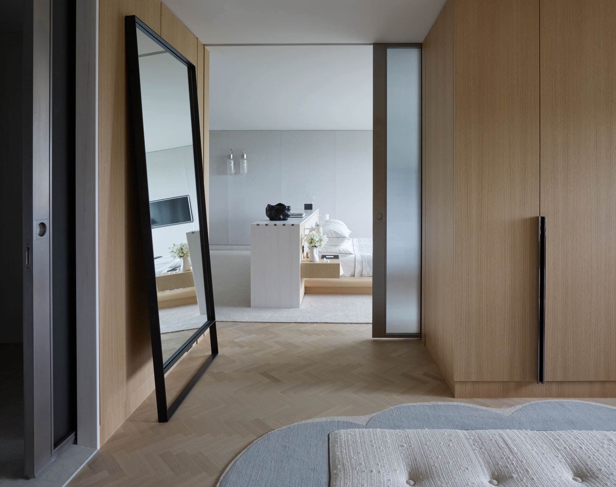 This view of the Master Dressing room in an apartment on Fifth Avenue in New York City which overlooks central Park.  The photograph shows a custom herringbone oak flooring and the master dressing room in milled white oak cabinetry with custom blackened chrome architectural hardware.