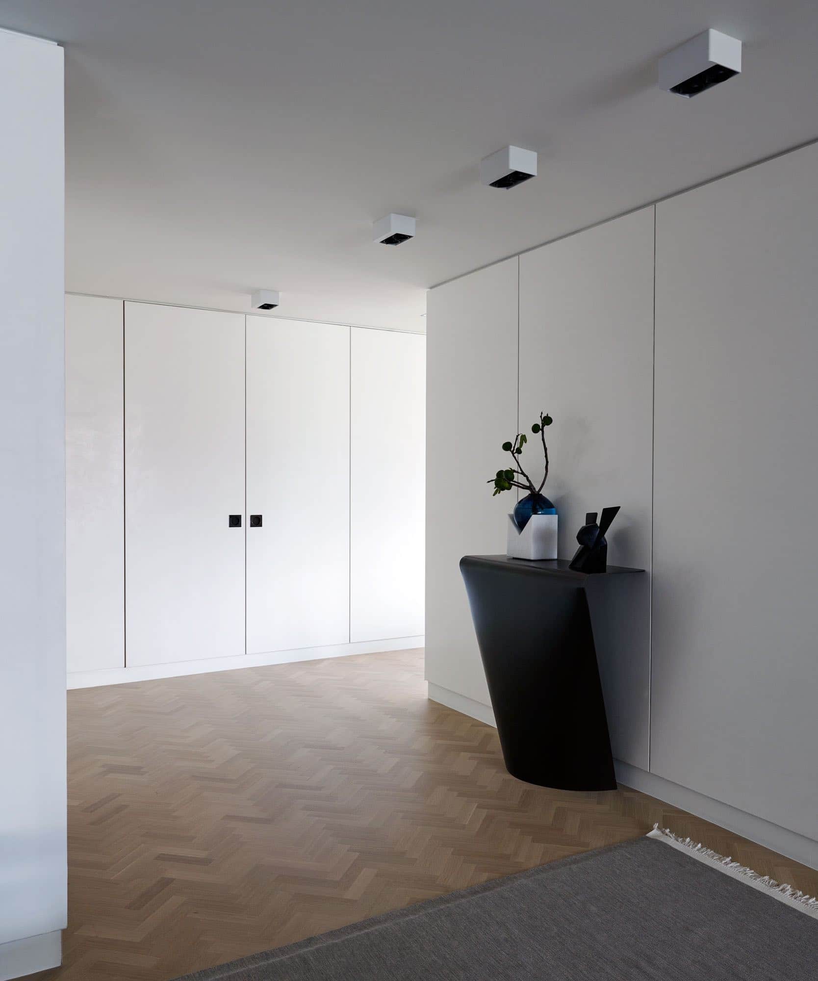 This photograph shows a gallery designed by Carol Egan with a concave console by Xavier Lust displaying a "Jokio" Sculpture of a Rabbit by Jacques Owczerak.  Custom rug by FJ Haikimian. The floors are a custom oak herringbone, and the walls are paneled and plastered.