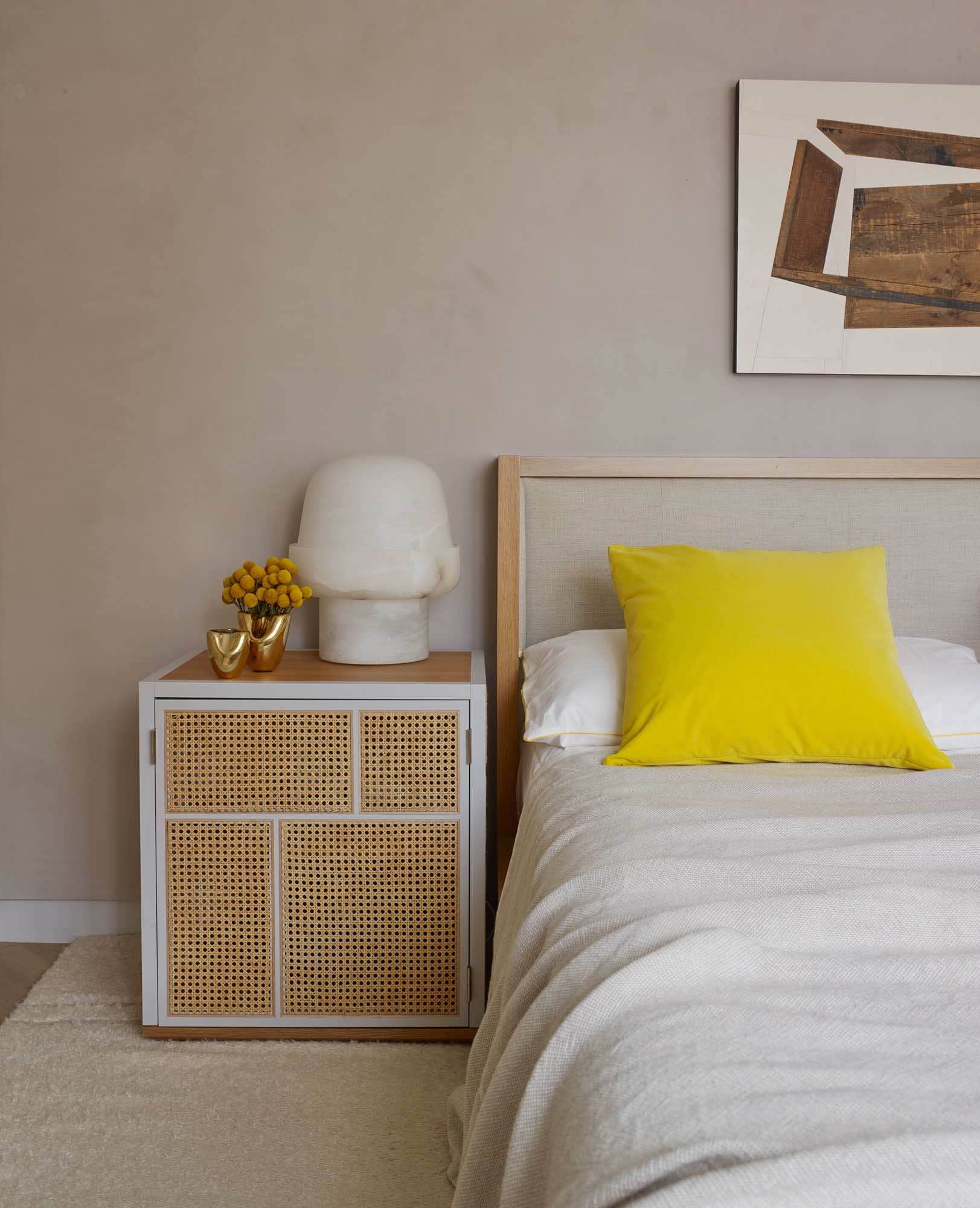 Shown in this image is a view of the guest bedroom designed by Carol Egan in a Fifth Avenue Apartment in New York.  A custom bedside grand light cabinet by Mathieu Gustafson in an oak and caned finish flank an oak and upholstered headboard in linen.  An alabaster BOB table lamp by Eric Schmitt is on the nightstand.  The "Found Box" woodcut by Michael Zelehoski hangs above the bed.