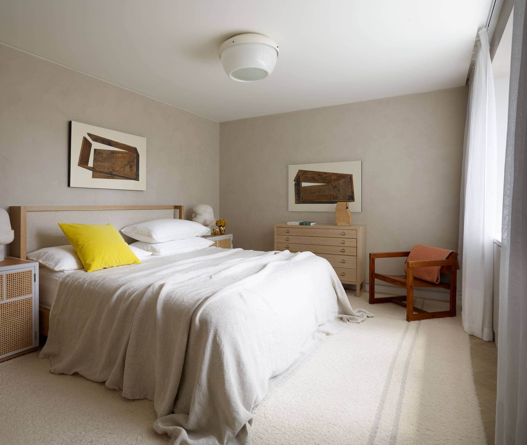 Designed by Carol Egan, this bedroom is in a residence on Fifth Avenue which overlooks Central Park in New York.    With an oak a linen upholstered bedframe, there is a linen bedspread that is draped over the bed in a casual style to the floor.  A woodcut entitled "Found Box" by Michael Zelehoski hangs above the bed.  Caned and wood bedside tables are designed by Mathieu Gustafson showcasing BOB Alabaster table lamps by Eric Schmitt.  The walls are the room are plastered in a putty color and the floors are a custom oak herringbone pattern in a natural finish.