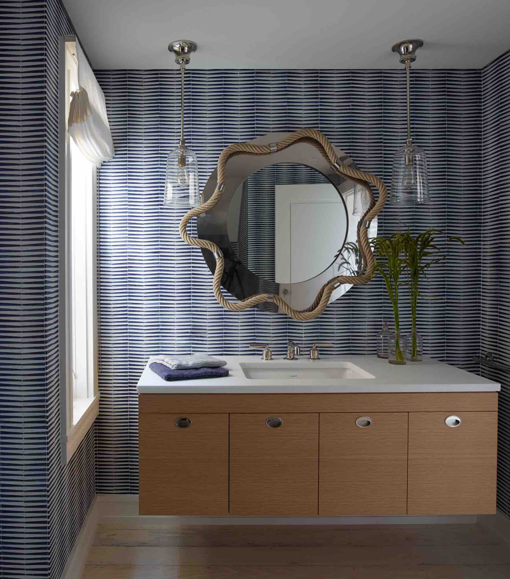 Honed Thassos marble and Lapis Lazuli stone wall tile create a striped pattern in this Hamptons powder room designed by Carol Egan.  Handblown Glass Henry Pendants by Waterworks flank a decorative mirror with rope and nickel accents designed by Thomas Boog, low profile Henry Faucet by Waterworks can be seen on the oak and white marble vanity.