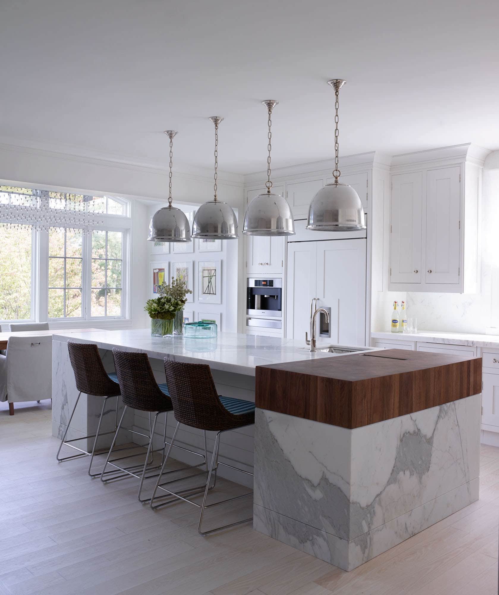 Designed by Carol Egan, the kitchen is shown in this image with "Oskar" hanging lights from Remains Lighting over the large marble and butcher block Island.  The kitchen Cabinets are from Peacock Kitchen.  Window treatment in Tropicale Mauritius linen fabric by Davis & Warshow.