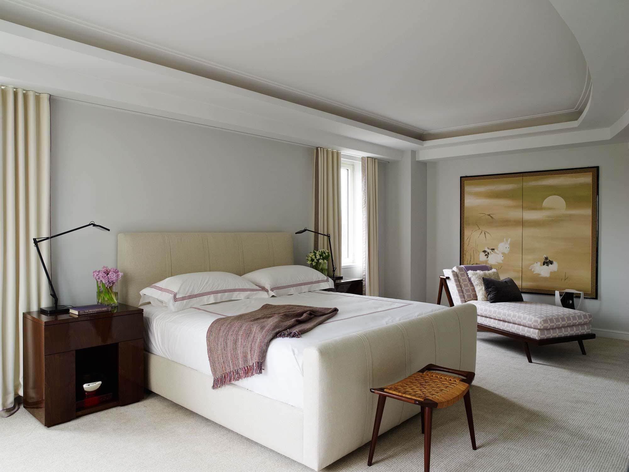 In the master suite of this fifth avenue apartment which overlooks Central Park, Carol Egan designed the bedside tables in walnut with table lamps by Flos.  The bed is a custom design with headboard and footboard upholstered in natural linen fabric.  The carpet is wall to wall installation of a hand-woven wool cut pile.