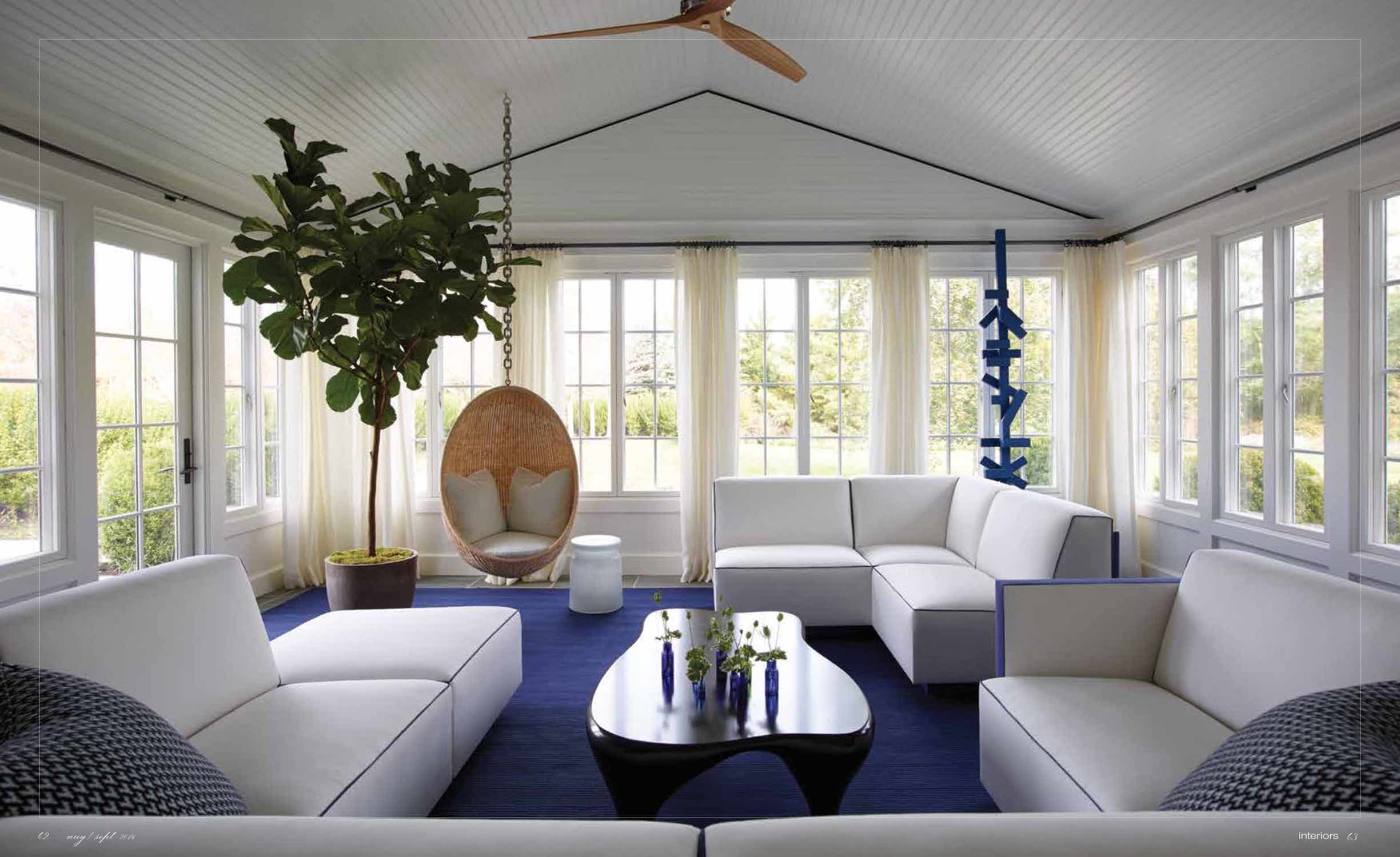 Shown here is a screened porch designed by Carol Egan with a Toro coffee table by Jacques Jarrige surrounded by a custom designed U-shaped sofa in white and contrast navy blue fabric.  The ceiling fan by Boffi and the area rug is a custom "Ray" Rug by Paola Lenti, which is designed for the outdoors.  A hanging egg chair by Nanna Ditzel has a shearling inset pillow and there is a Blue Sculpture by Sidney Geist in the corner of the room.