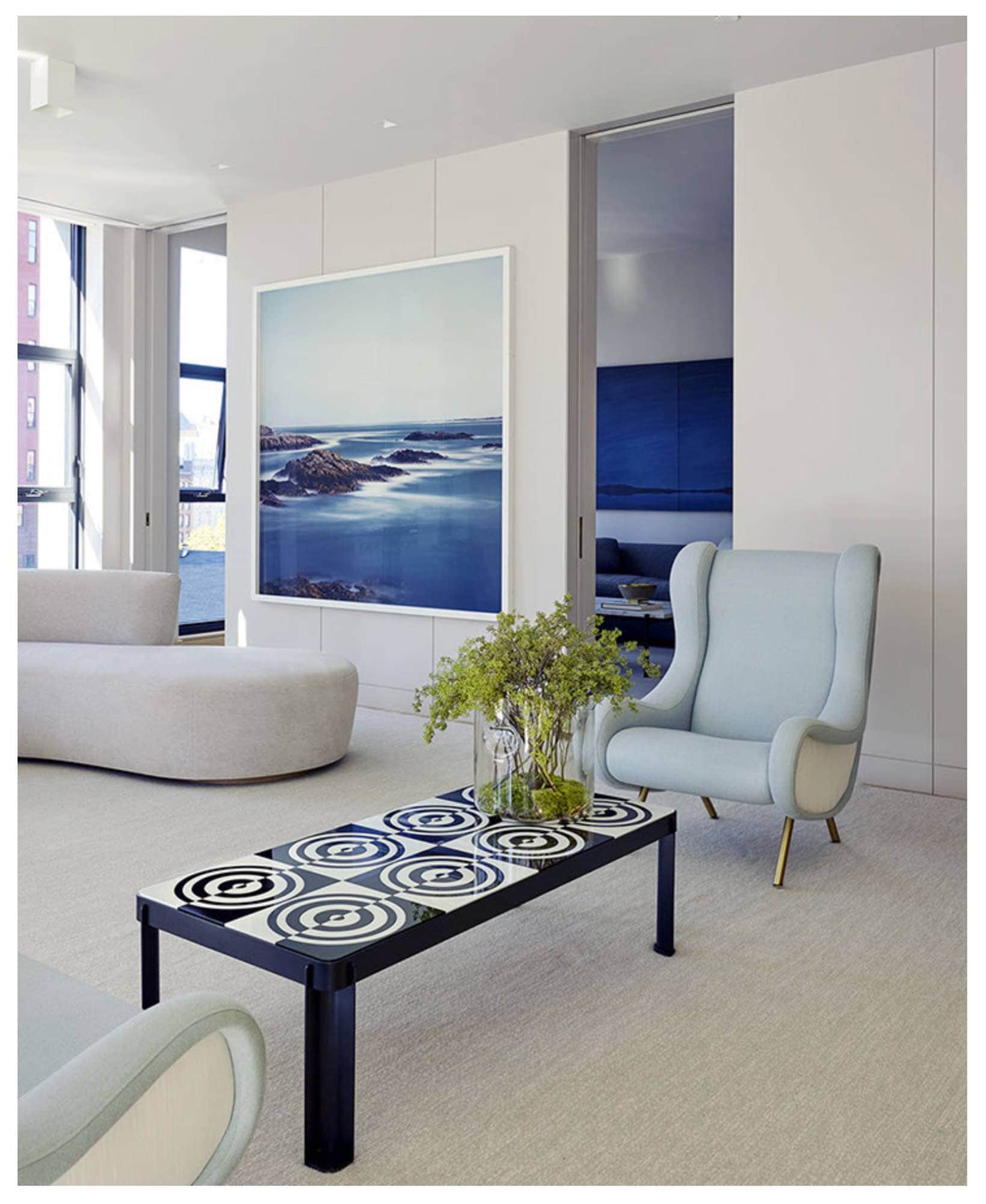 This image shows the living area of the loft, designed by Carol Egan Interiors, from a different angle facing into the adjoing Family TV room through pocketed doors.  Two Vintage Senor Chairs are flanked by a Robert Riida Murano glass optical top and metal coffee table.  Artwork by Darren Almond in the background.